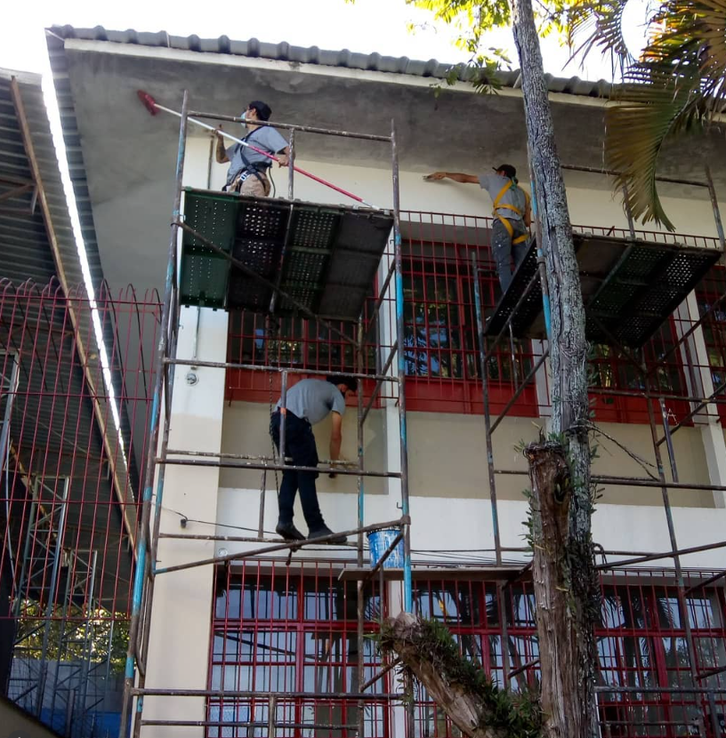 Profissionais realizando pintura do lado de fora de uma escola